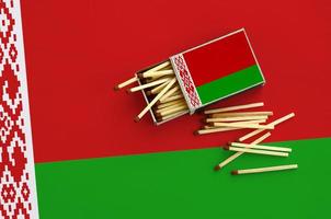 Vitryssland flagga är visad på ett öppen tändsticksask, från som flera tändstickor falla och lögner på en stor flagga foto