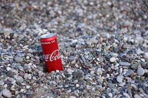 antalya, Kalkon - Maj 18, 2021 original- coca cola röd tenn kan lögner på små runda sten stenar stänga till hav Strand. Coca Cola på turkiska strand foto