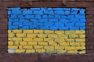 gammal tegel vägg målad i de färger av de ukrainska flagga foto