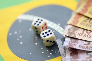 tärningar kuber med brasiliansk pengar räkningar på flagga av brasil republik. begrepp av tur och hasardspel i brasil foto