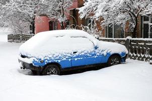 Foto av en bil täckt i en tjock lager av snö. konsekvenser av tung snöfall