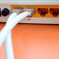 de internet kabel- pluggar är ansluten till de internet router, som lögner på en ljus orange bakgrund. objekt nödvändig för internet förbindelse foto