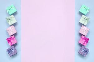 små gåva lådor av annorlunda färger med band lögner på en violett och rosa bakgrund foto