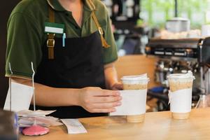 Barista tjänande is kaffe till kund i Kafé kaffe affär. foto