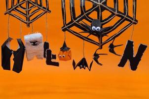 de origami halloween bakgrund av pumpa huvud domkraft o lykta mamma fladdermus och nunna hängande på Spindel spindelnät uppsättning till de ord halloween isolerat på orange. foto
