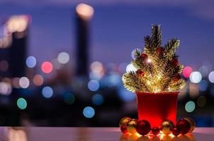 jul träd dekorerar med struntsak ornament och lampor sätta på tabell med färgrik stad bokeh lampor bakgrund. foto