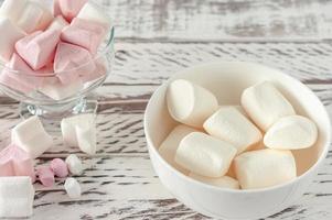 blandad rosa och vit marshmallows i glas koppar på trä- bakgrund. hjärta form marshmallow för varm choklad eller kakao foto