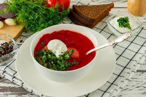traditionell ukrainska ryska borscht med vitlök och bröd. en skål av röd rödbeta borscht på en vit trä- tabell. rödbeta soppa. traditionell slavic kök. foto