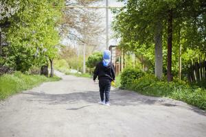 wander ensam längs en lantlig gata. en liten pojke är gående genom de landsbygden. foto