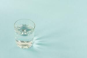 en glas av ren vatten på blå bakgrund. kopia Plats för text. konsept av healt liv och diet foto