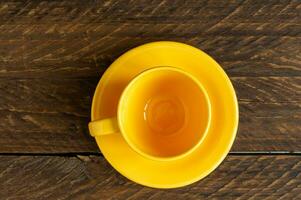 topp se av tömma gul kopp och fat på trä- rustik bakgrund. kök porslin foto
