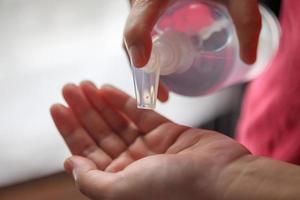kvinna använder sig av alkohol desinfektionsmedel gel gnugga för rengöring hand covid-19 korona virus förebyggande begrepp foto