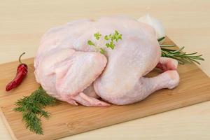 rå kyckling på trä- styrelse och trä- bakgrund foto