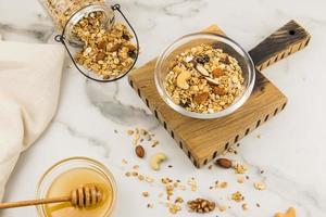 hemlagad granola med honung i en glas skål på en trä- kök styrelse och marmor tabell. friska äter. foto