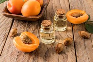 aprikos olja i glas flaskor på de bakgrund av mogen aprikoser och frön. trä- bakgrund. de begrepp av föryngring, fuktgivande de hud. foto