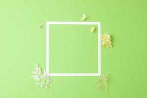 kosmetisk bakgrund med blommor och vit ram på grön. platt lägga, kopia Plats foto