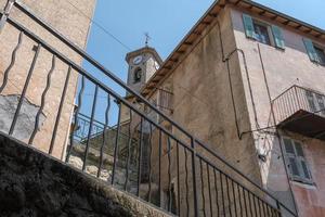 sten torn med klocka och klocka, upp se till de klocka torn, gammal kyrka med en Kolla på, en små by i de bergen i Frankrike, europeisk sten kapell i de townlet, gammal Europa stad arkitektur. foto