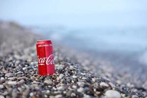 antalya, Kalkon - Maj 18, 2021 original- coca cola röd tenn kan lögner på små runda sten stenar stänga till hav Strand. Coca Cola på turkiska strand foto