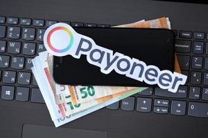 ternopil, ukraina - september 6, 2022 betalare papper logotyp lögner på svart bärbar dator med euro räkningar. betalare är amerikan finansiell tjänster företag den där tillhandahåller uppkopplad pengar överföra foto