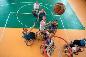 Inaktiverad krig eller arbete veteraner blandad lopp och ålder basketboll lag i rullstolar spelar en Träning match i en sporter Gym hall. handikappade människor rehabilitering och inkludering begrepp. foto