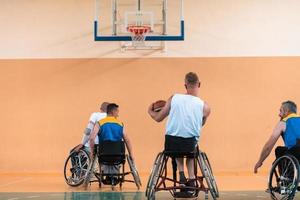 Inaktiverad krig veteraner blandad lopp och ålder basketboll lag i rullstolar spelar en Träning match i en sporter Gym hall. handikappade människor rehabilitering och inkludering begrepp foto