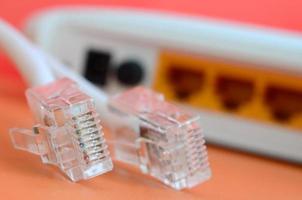 internet router och internet kabel- pluggar lögn på en ljus orange bakgrund. objekt nödvändig för internet förbindelse foto
