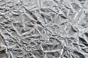 tunn rynkig ark av krossad tenn aluminium silver- folie bakgrund med skinande skrynkliga yta för textur foto