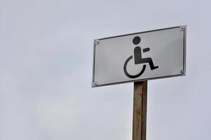 en väg tecken indikerar de korsning av en väg för Inaktiverad människor. vit väg tecken med en bild av en man Sammanträde i en rullstol foto