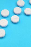 en få vit tabletter lögn på en ljus blå bakgrund yta. bakgrund bild på medicinsk och farmaceutisk ämnen foto