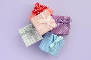 lugg av en små färgad gåva lådor med band lögner på en violett bakgrund. minimalism platt lägga topp se foto