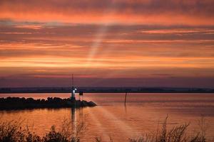 solnedgång i Sverige på de hamn av sjö vaettern. fyr i de bakgrund foto