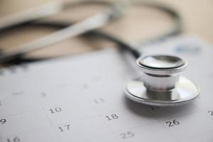 stetoskop med kalender sida datum på trä tabell bakgrund läkare utnämning medicinsk begrepp foto