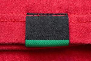 svart tom tvätt vård kläder märka på röd bomull skjorta bakgrund foto