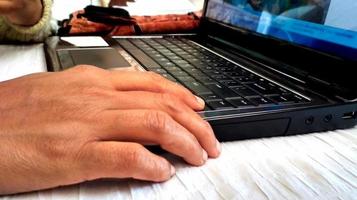 stänga upp på kvinnas händer använder sig av henne bärbar dator foto