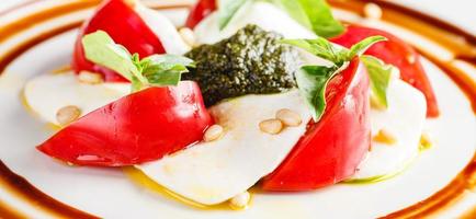 caprese sallad med mozzarella, tomat, basilika och pesto foto