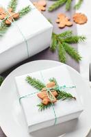 jul festlig tabell miljö, tallrik med gåva dekorerad med gran kvistar och pepparkaka foto