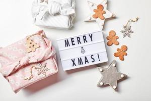 ljus låda inskrift glad jul, gåvor i japansk furoshiki stil och pepparkaka småkakor foto