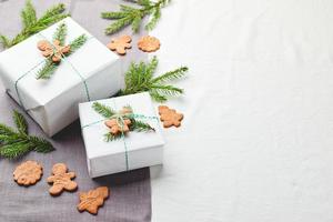 jul gåvor insvept i vit papper och dekorerad med gran kvistar och pepparkaka småkakor foto