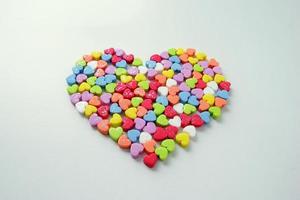 en massa av de liten lysande färgrik hjärtan i ett stor hjärta för hjärtans dag. foto