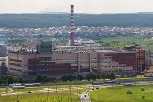 ariel panoramautsikt över staden och skyskrapor med en enorm fabrik med rökande skorstenar i bakgrunden foto