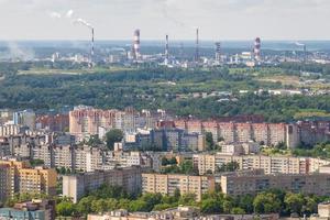 ariel panoramautsikt över staden och skyskrapor med en enorm fabrik med rökande skorstenar i bakgrunden foto