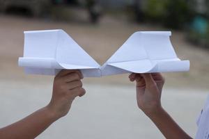 hand av barn innehav papper flygplan vika ihop från återanvändning papper. den är en leksak född av kreativitet och fantasi. foto