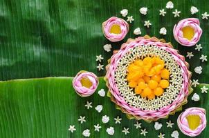 thai bröllop desserter på tallrik eller krathong tillverkad från rosa lotus kronblad och krona blomma för thai traditionell ceremoni på banan blad bakgrund. foto