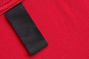 tom svart tvätt vård kläder märka på röd tyg textur bakgrund foto