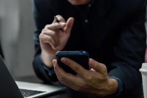 man hand innehav mobil smartphone digital teknologi nätverk kommunikation på skrivbord. foto