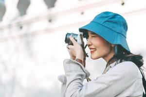 attraktiv ung vuxen asiatisk kvinna resenär som använder kameran för foto resa.