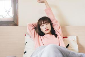 vakna upp arm sträcka asiatisk tonåring kvinna i sovrummet. foto