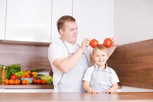 leende far och son har roligt innehav röd klocka paprikor i de form av öron foto