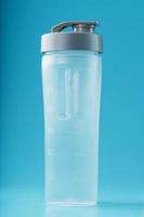 shaker är ett tömma plast smoothie kopp på en blå bakgrund. foto