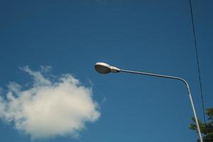 modern elektricitet lampa posta med blå himmel och moln som bakgrund. stål gata ljus eller lykta på Pol i de dagtid är konceptualiseras i industriell, teknologisk, och urbanisera foto